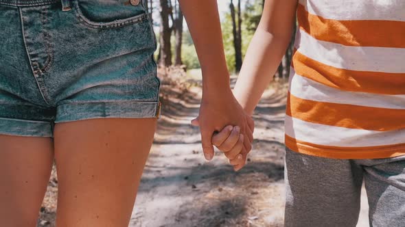 Young Mother and Son Holding Hands Walking Along a Path in Forest. Slow Motion