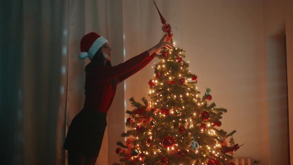 Girl decorates the Christmas tree in the night