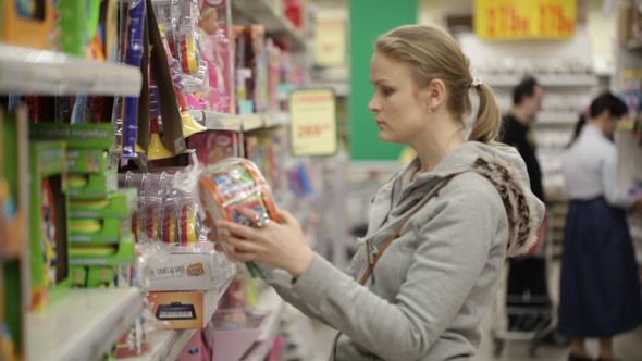 Young Woman is Choosing Toys in the Supermarket