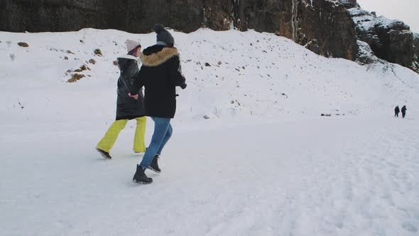 Happy Young Girlfriends Running to Waterfall in Iceland