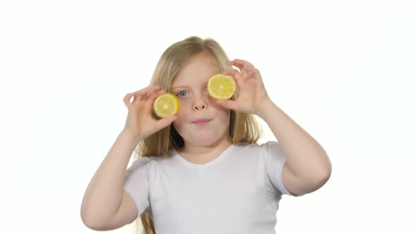 Little Girl Closes Her Eyes with a Lemon and Shows Different Emotions, Licks It and Croaks. White