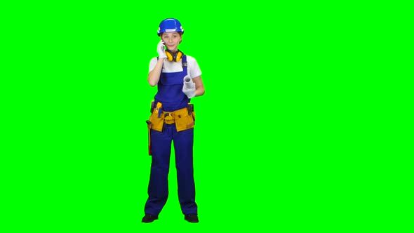 Builder Is Standing and Talking on the Phone with a Drawing in Her Hands. Green Screen