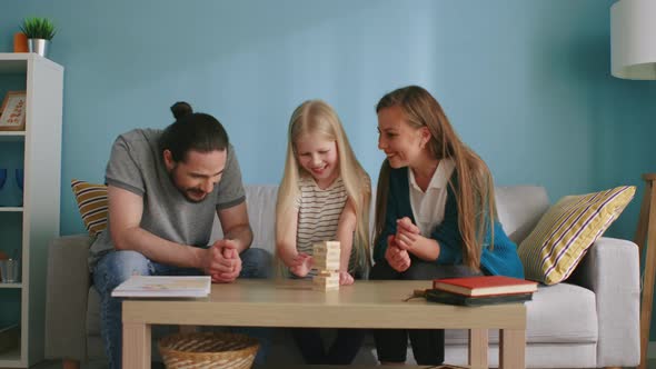 Small Girl Plays Jenga with Mom and Dad