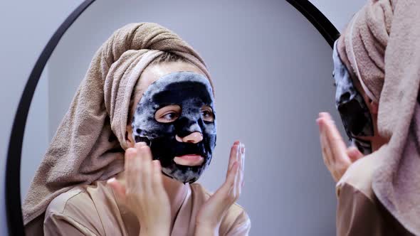 Young woman applying face mask in bathroom and smiling