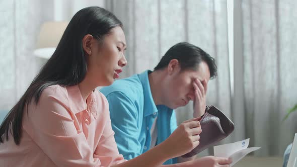 Asian Couple Looking At The Bill And Checking Money On The Purse Then Having Headache