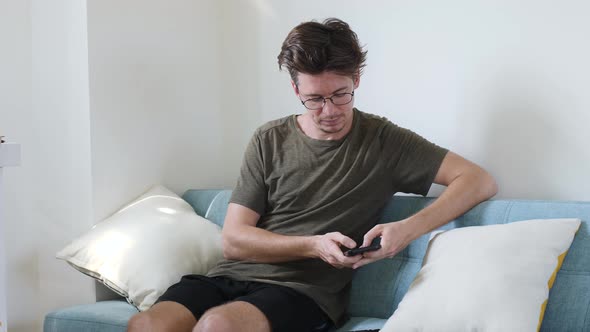 Frustrated Young Man Looking at Smartphone Screen Feeling Disappointed with Received Bad News