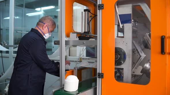 A man works at a machine for the manufacture of medical masks with nanofiber.