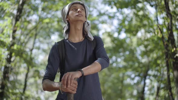 Young Mixed-race Male Refugee Standing in Sunlight in Summer Forest and Looking Around. Portrait of