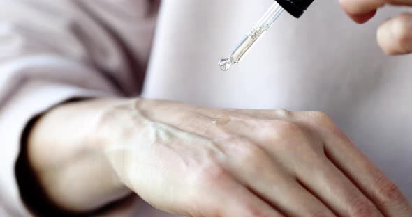 Woman Dripping Essential Oil on Skin of Hands Closeup