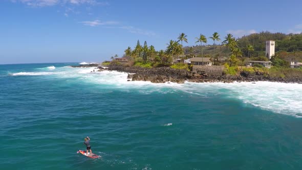 Aerial view of a man sup stand-up paddleboard surfing in Waimea, Hawaii