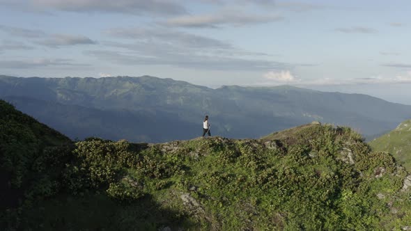 Aerial View Tracking Shot Active Sports Woman Hiking with Sticks on Natural Mountain Ridge Valley