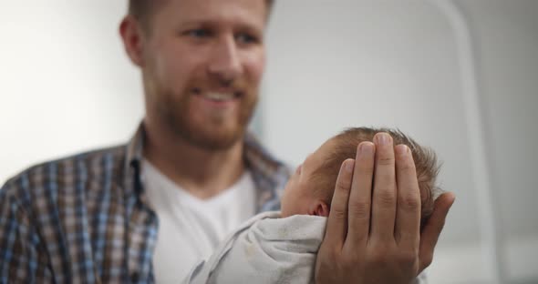 Closeup Portrait of Young Father Holding Newborn Baby in Hospital