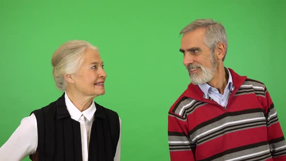 An Elderly Man and Woman Lean Into the Phrame and Smile at the Camera - Green Screen Studio