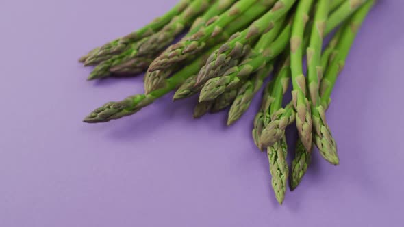 Video of close up of fresh asparagus with copy space over lilac background