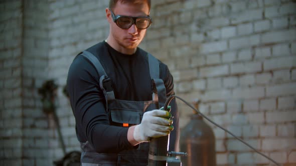 Young Handsome Man Using a Grinder To Cut the Metal Detail