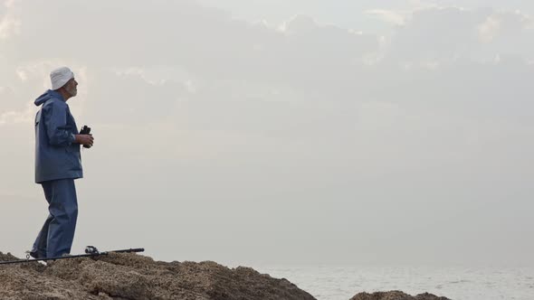 Old fisherman looking into the ocean using his binoculars