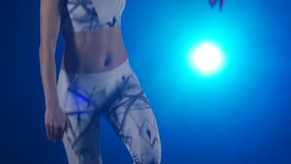 Athletic Body Jumping Against Blue Spotlight. Slow Motion. Close-up