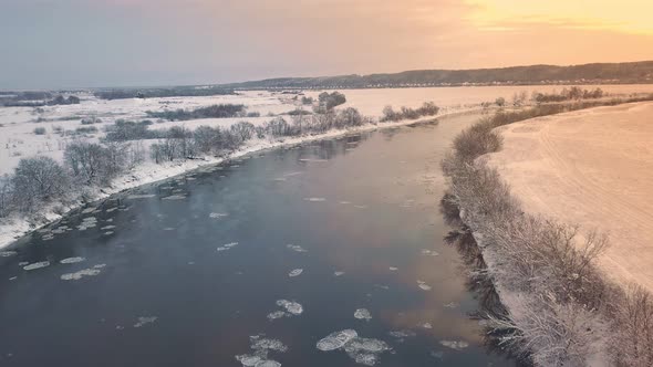 Amazing winter landscape with red sunrise. Drone flying over the river