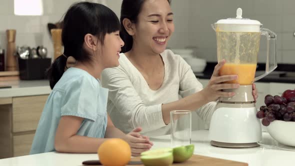 Mother and daughter making orange smoothie