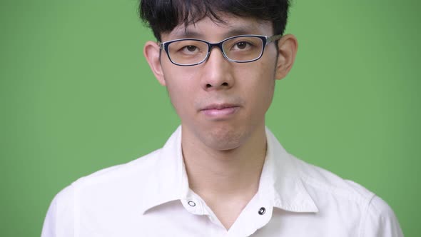Head Shot of Young Asian Businessman Against Green Background