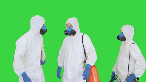 Three Disinfectors Walk in Holding the Disinfectant in Their Hands on a Green Screen, Chroma Key