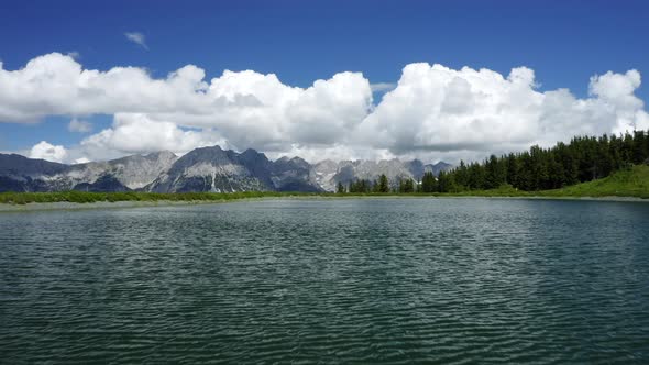 Aerial Fly Above Water Surface of Mountain Lake Near Ellmau Wilderkaiser Mountains in Background