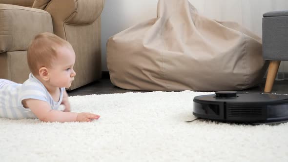Little Baby Boy and Robot Vacuum Cleaner Approaching and Getting Closer on Carpet in Living Room