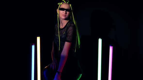 Young Attractive Woman with Yellow Hair Sitting Near Colorful Neon Tube Lights