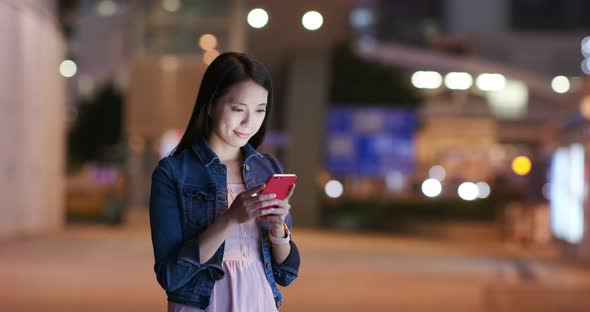 Young woman check on mobile phone in city at night