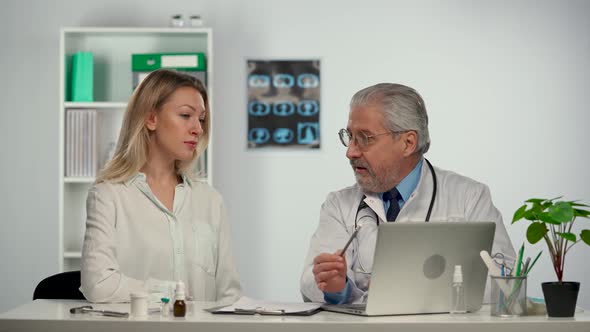 Family Doctor Talks and Displays Information on a Computer During a Patient Consultation at a