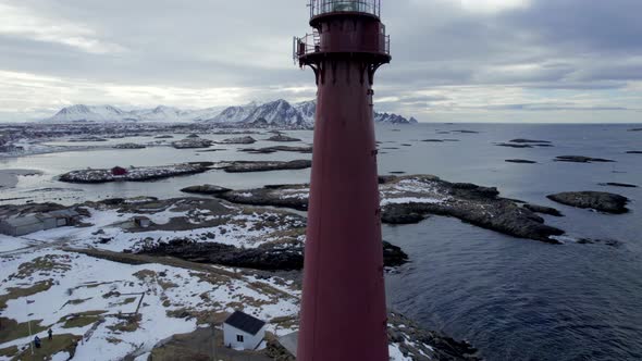 Beautiful aerial pedestal shot of the Andenes Lighthouse in Norway with the snow speckled rocky shor