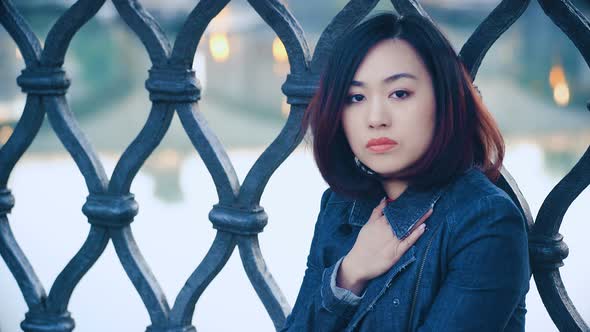 serious asian woman looking in camera on city background: Pensive chinese woman