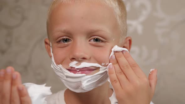 A Little Boy is Playing with Shaving Foam at Home in the Bathroom