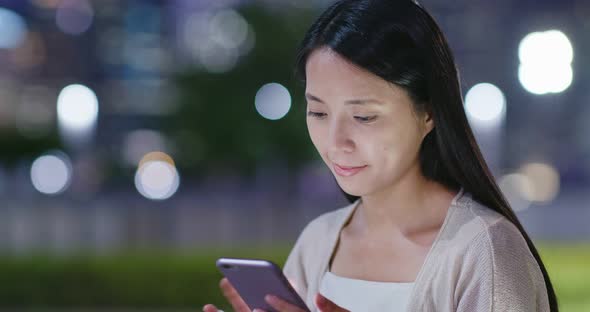 Woman use of mobile phone online in city at night