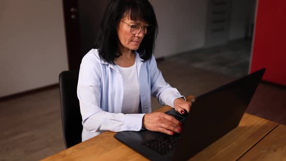 Mature woman typing on laptop modern technologies