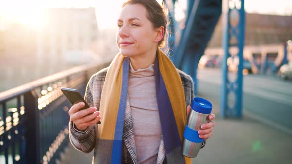 Portrait of a Young Caucasian Businesswoman in a Coat Walking Across the Bridge on a Frosty Morning