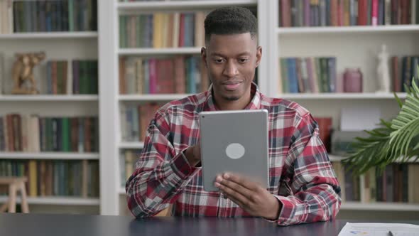 African Man Celebrating Success on Tablet in Office