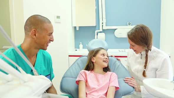 Friendly dental assistant and dentist talking with cute little patient