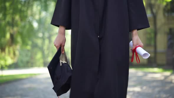 Dolly Shot of Unrecognizable Slim Young Caucasian Woman in Graduation Toga Walking at University