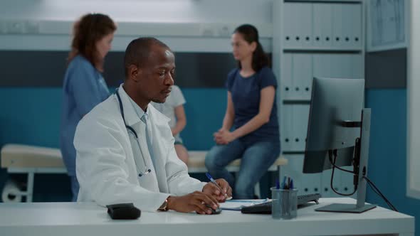 African American Physician with Stethoscope Working on Computer