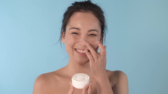 Asian woman applying cream on the nose.