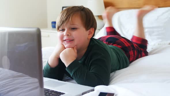 Boy using laptop in bedroom