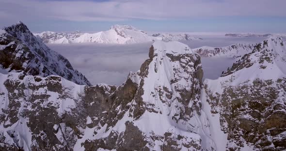 Aerial drone view of a skier skiing down a steep snow covered mountain.