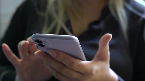 Woman Sitting at Home Looks at Phone Screen and Typing a Message Closeup Shot