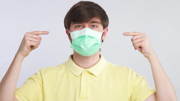 Man Poiting with Both Finger To Sterile Protective Mask on His Face with Big Attention