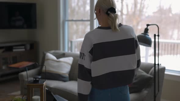 woman walking to the couch to lay down and scroll through tablet while drinking coffee in a nice hou