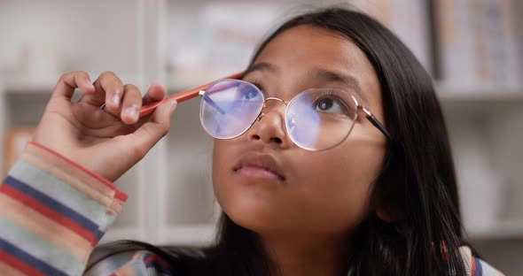 Girl glasses thinking while sitting at classroom