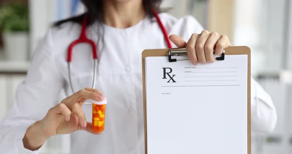 Doctor Holding in Hands Clipboard with Prescription and Jar of Medical Capsules Closeup Movie Slow