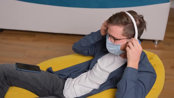 Young Man Listening To Music on Headphones While Is Sitting on a Bean Bag