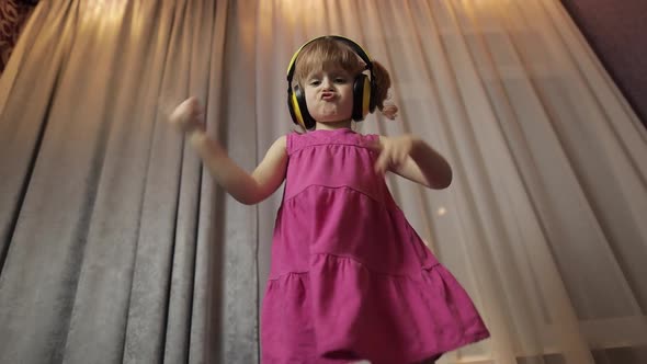 Little Child Girl in Wireless Headphones Enjoying Listen Music. Dancing at Home